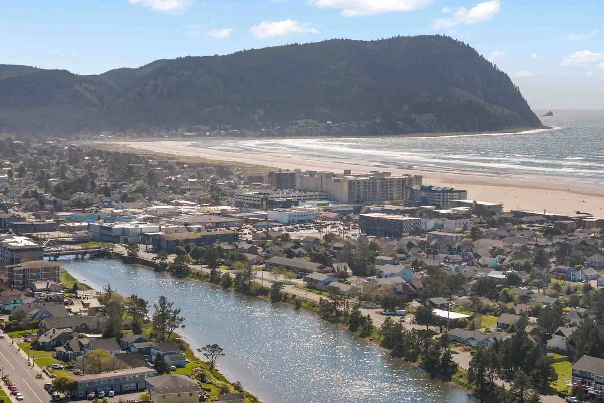 A sweeping view of the coastal landscape, including the ocean, river, a charming townscape, and distant mountains. The image captures the intersection of nature and community, illustrating the scenic beauty and recreational opportunities available just beyond the home.