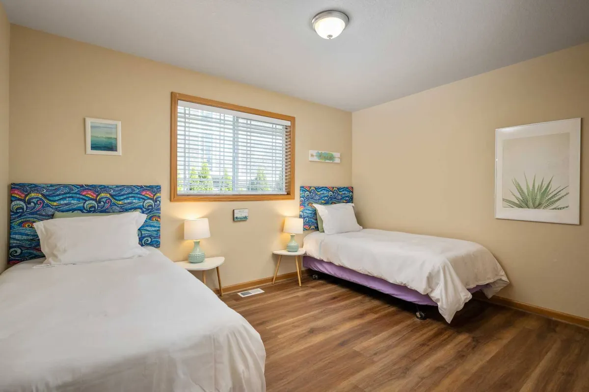 A cheerful bedroom adorned with colorful headboards, bedside lamps, and a window that lets in abundant natural light. The decor is playful yet comfortable, offering a welcoming space for both families and couples to relax and recharge.
